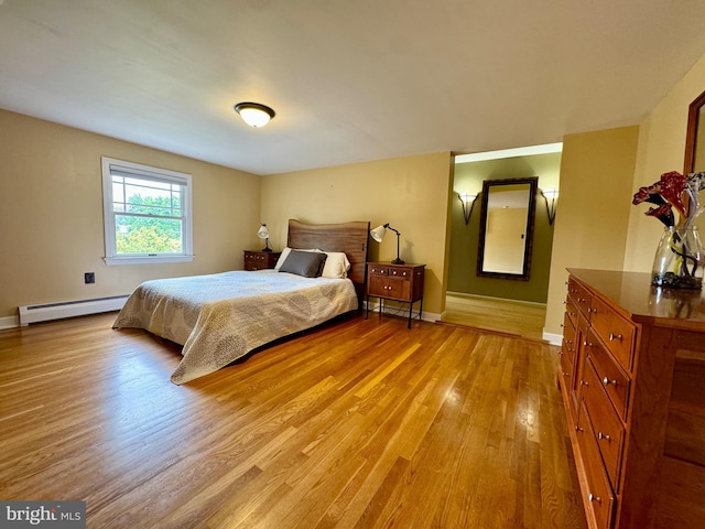 bedroom featuring a baseboard heating unit and light hardwood / wood-style flooring