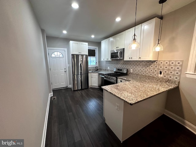 kitchen featuring kitchen peninsula, white cabinets, light stone counters, stainless steel appliances, and dark hardwood / wood-style floors