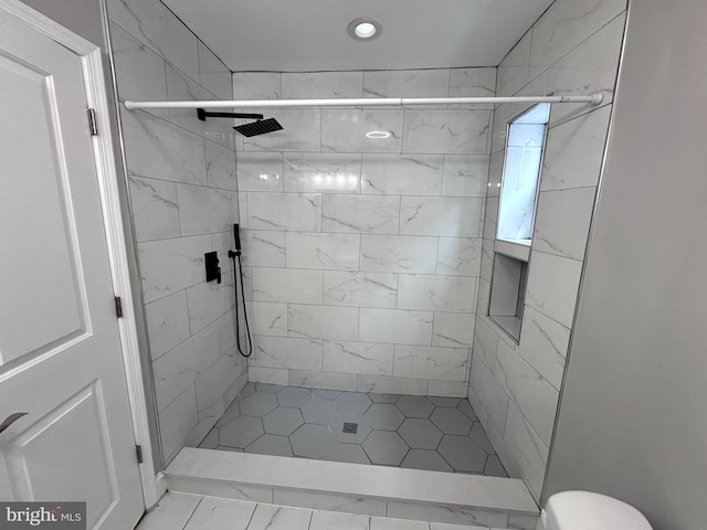 bathroom with tiled shower and tile patterned floors