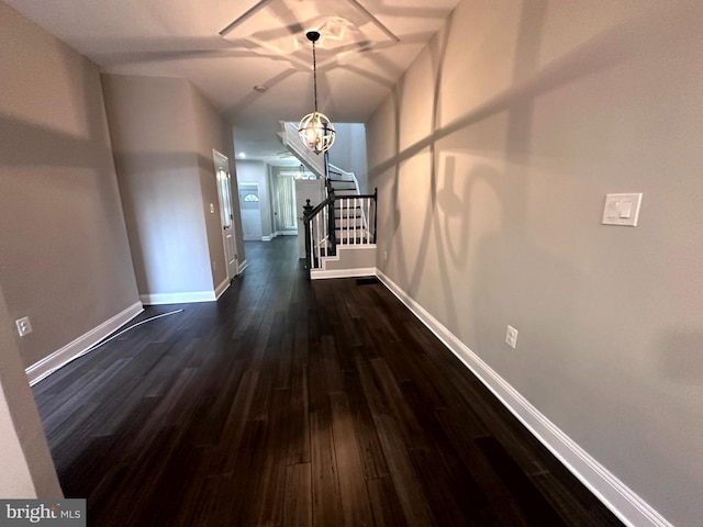 hallway with dark wood-type flooring and a notable chandelier