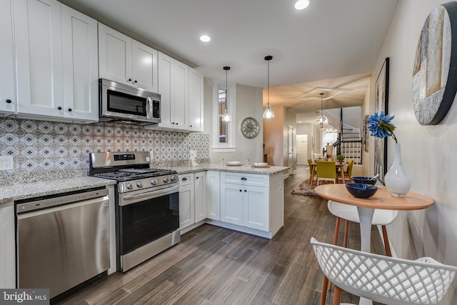 kitchen featuring stainless steel appliances, white cabinets, light stone counters, decorative backsplash, and dark hardwood / wood-style flooring