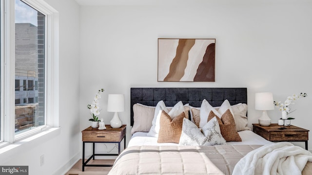 bedroom with multiple windows and light wood-type flooring