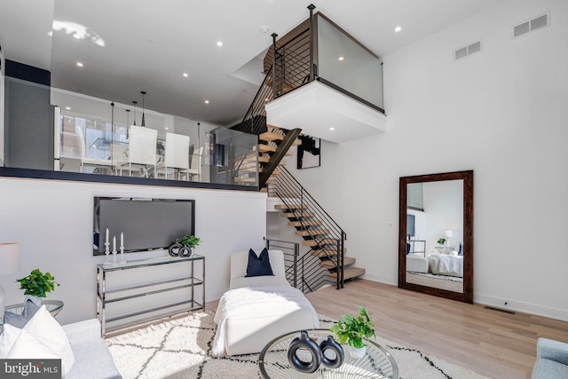 living room featuring a towering ceiling and light hardwood / wood-style floors