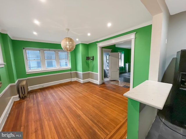 unfurnished dining area featuring hardwood / wood-style floors and radiator heating unit