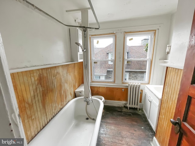 bathroom featuring vanity, a tub to relax in, radiator heating unit, and wooden walls