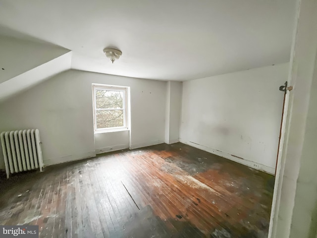 additional living space featuring dark hardwood / wood-style flooring, radiator, and vaulted ceiling