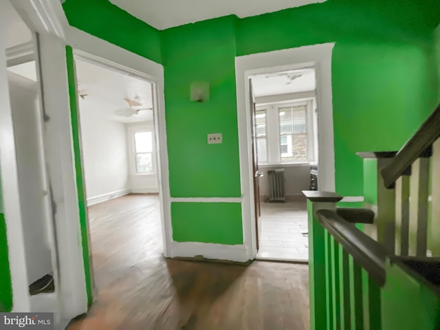 corridor with hardwood / wood-style floors and radiator heating unit