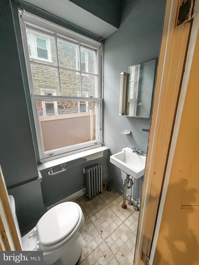 bathroom featuring sink, radiator heating unit, and toilet