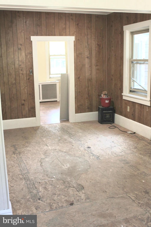 empty room featuring wood walls and radiator heating unit