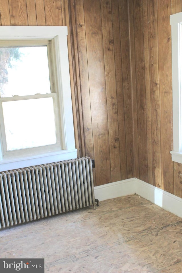 spare room featuring radiator heating unit and wooden walls