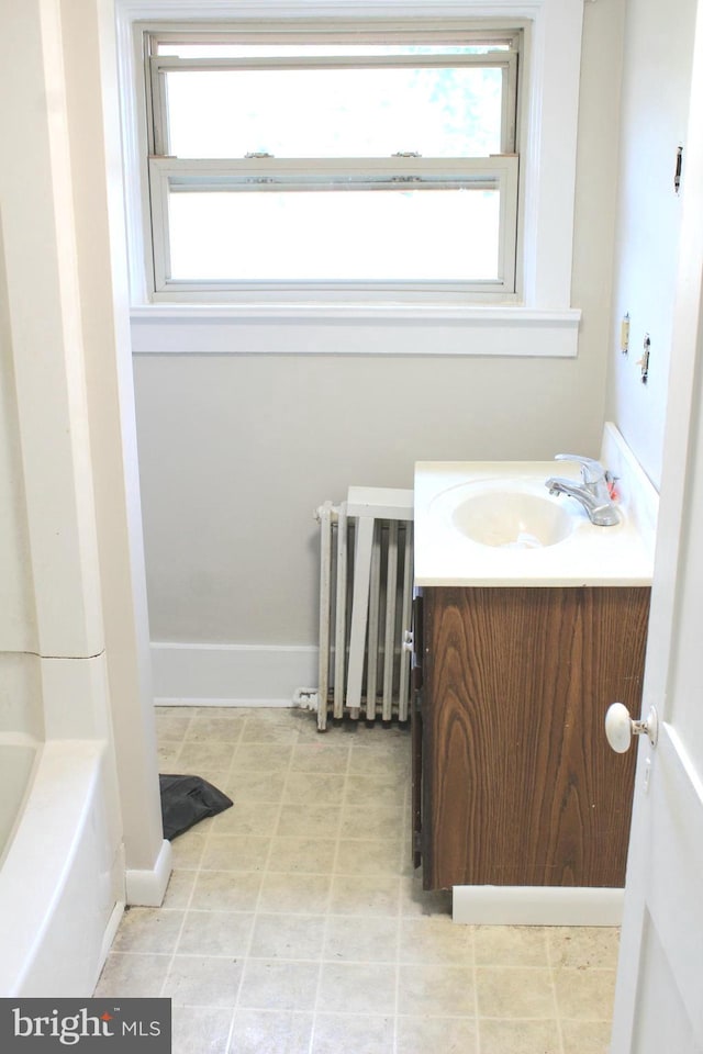 bathroom with a bath, vanity, and radiator heating unit