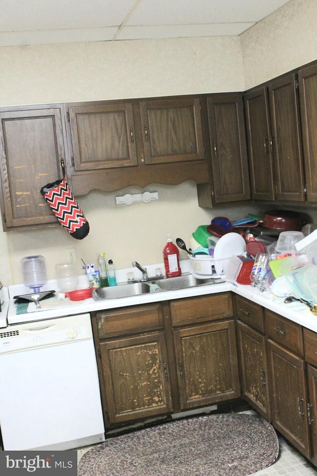 kitchen featuring dark brown cabinetry, white dishwasher, and sink