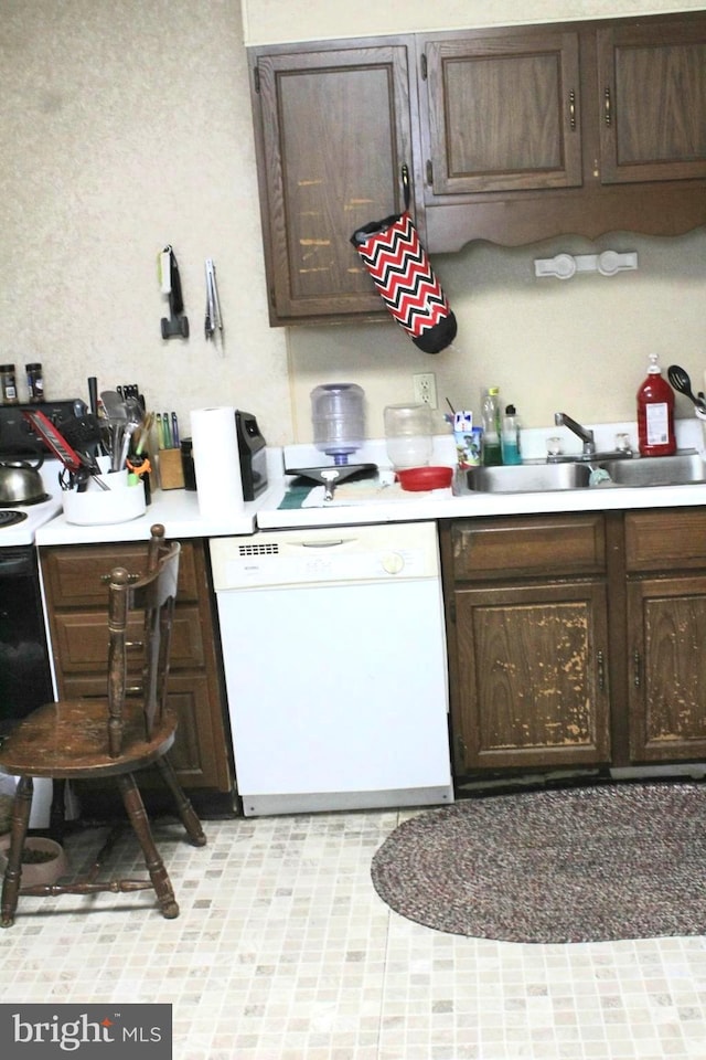 kitchen with dark brown cabinetry, white appliances, and sink