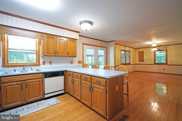 kitchen with dishwasher, kitchen peninsula, a healthy amount of sunlight, and light wood-type flooring