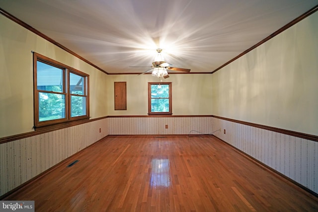 empty room featuring hardwood / wood-style flooring, ceiling fan, and crown molding