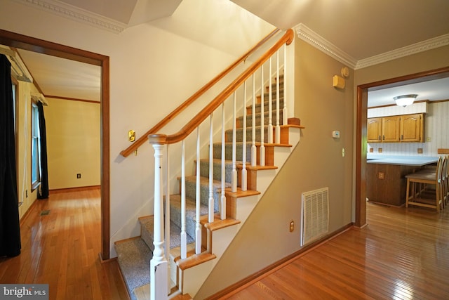 staircase with hardwood / wood-style floors and crown molding