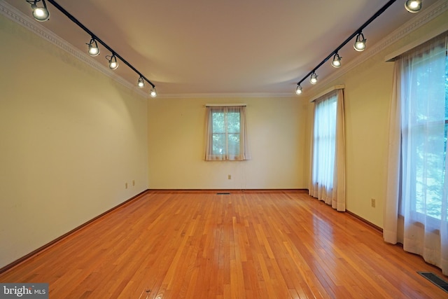 unfurnished room featuring rail lighting, light wood-type flooring, and crown molding