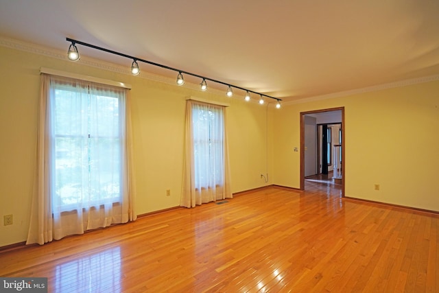 spare room with ornamental molding, track lighting, and light hardwood / wood-style flooring