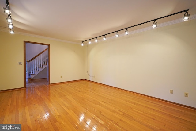 spare room with track lighting, hardwood / wood-style flooring, and crown molding