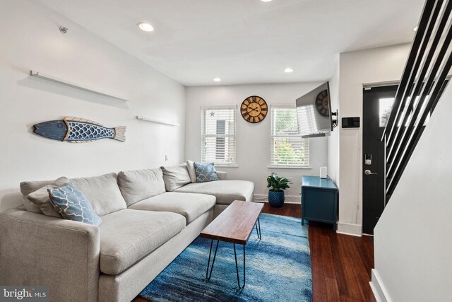 living room featuring dark wood-type flooring and ceiling fan