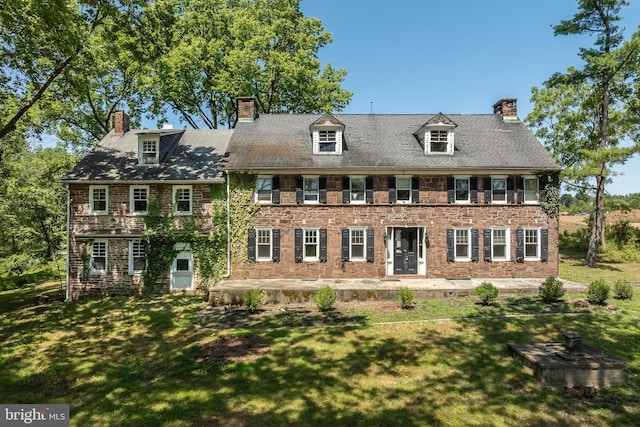 colonial home featuring a front lawn and a patio