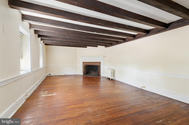 unfurnished living room featuring hardwood / wood-style flooring, radiator heating unit, a fireplace, and beamed ceiling