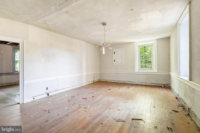 empty room with an inviting chandelier and light hardwood / wood-style flooring