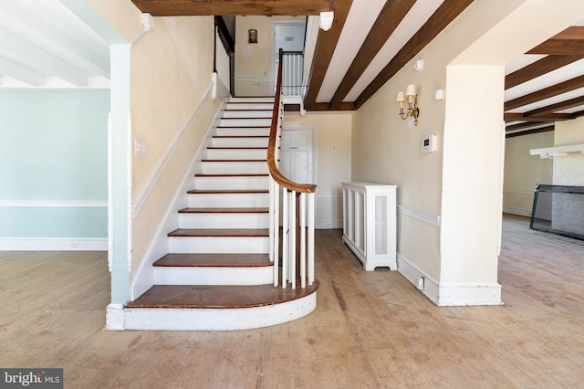 staircase featuring wood-type flooring and beam ceiling