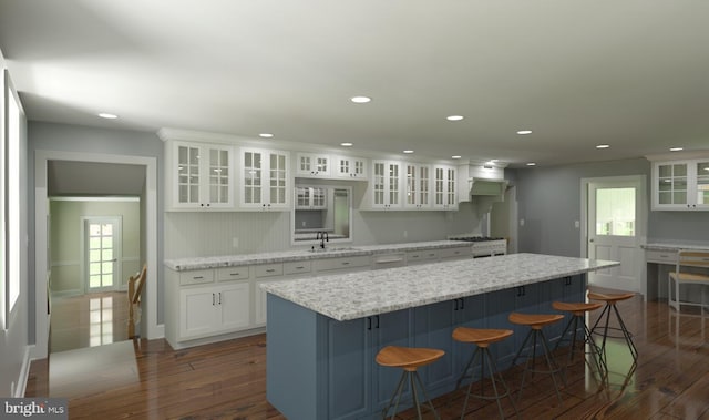 kitchen featuring white cabinetry, a kitchen island, dark hardwood / wood-style floors, and a kitchen breakfast bar