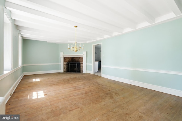 unfurnished living room featuring hardwood / wood-style flooring, a chandelier, and beam ceiling