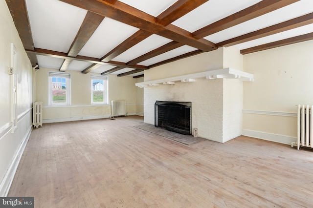 unfurnished living room with radiator heating unit, a fireplace, and light hardwood / wood-style flooring