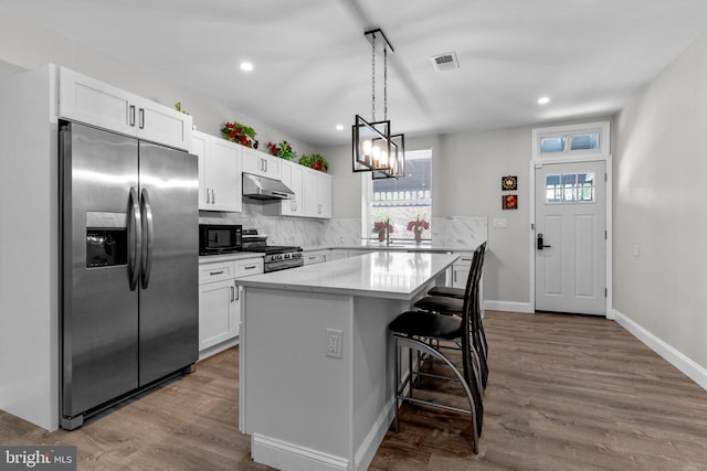 kitchen featuring a center island, appliances with stainless steel finishes, dark hardwood / wood-style flooring, a kitchen breakfast bar, and white cabinets