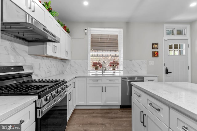 kitchen featuring stainless steel appliances, sink, white cabinets, and light stone counters