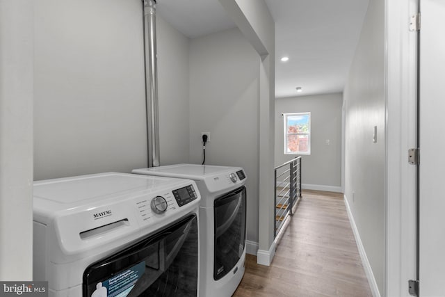 washroom with washing machine and clothes dryer and light wood-type flooring