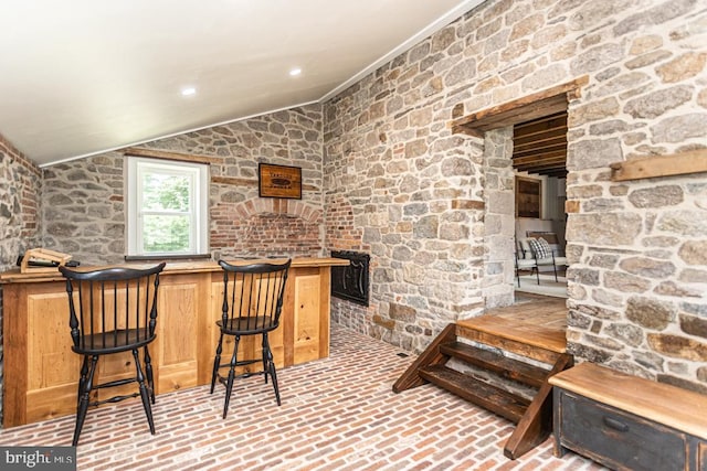 bar featuring crown molding, lofted ceiling, and a fireplace