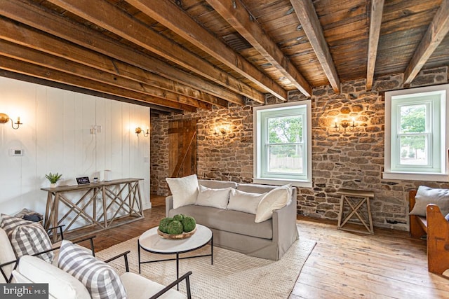 living room featuring beam ceiling, wooden ceiling, a healthy amount of sunlight, and light wood-type flooring