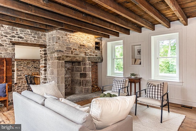 living room featuring light hardwood / wood-style flooring, beam ceiling, wooden walls, a fireplace, and wooden ceiling