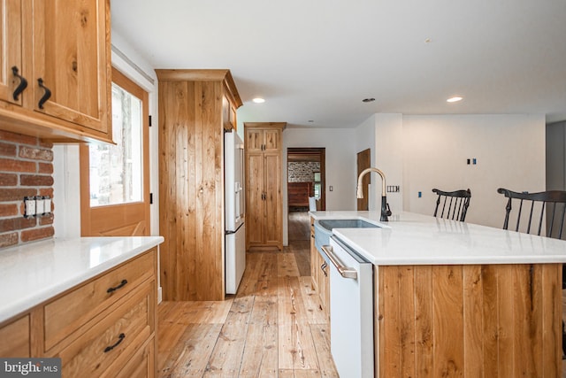 kitchen featuring white appliances, tasteful backsplash, light hardwood / wood-style floors, an island with sink, and a kitchen bar