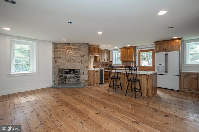 kitchen featuring light hardwood / wood-style flooring, high end white refrigerator, a breakfast bar, and a kitchen island