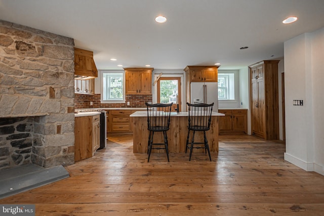 kitchen featuring tasteful backsplash, a center island, high quality fridge, a fireplace, and hardwood / wood-style floors