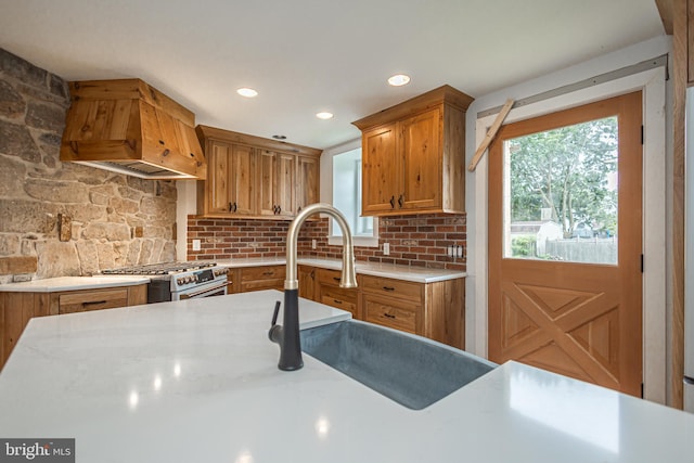 kitchen with premium range hood, sink, high end stove, and backsplash