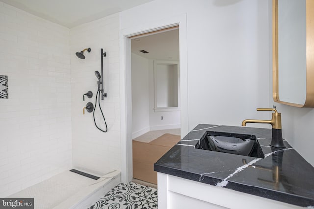 bathroom featuring a tile shower and sink