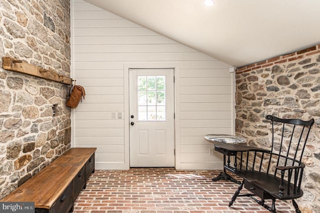 mudroom featuring lofted ceiling and wood walls