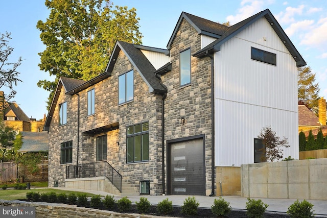 exterior space with stone siding, a shingled roof, and fence