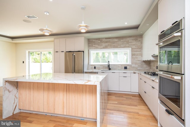 kitchen featuring white cabinets, tasteful backsplash, light hardwood / wood-style floors, and stainless steel appliances