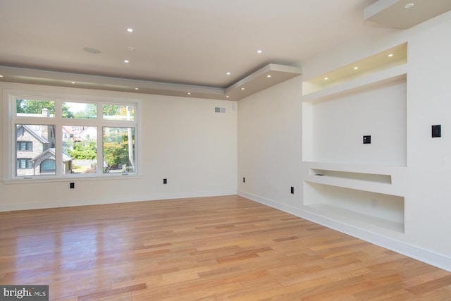 empty room featuring built in shelves and light wood-type flooring