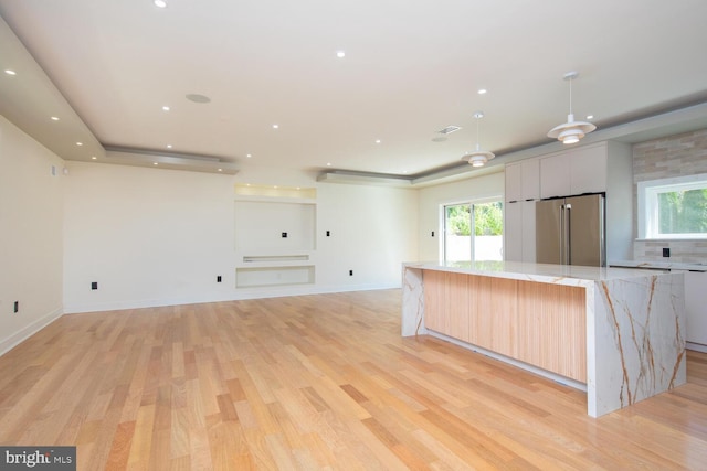 kitchen with a center island, light hardwood / wood-style floors, light stone counters, and high end refrigerator