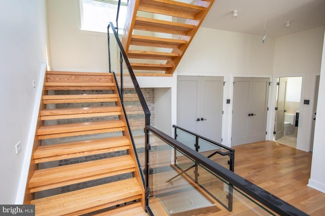 staircase featuring a high ceiling and wood-type flooring