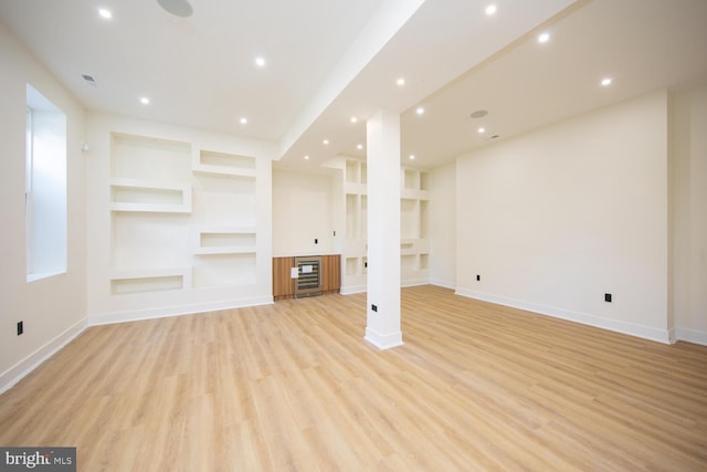 unfurnished living room featuring light hardwood / wood-style floors and built in shelves