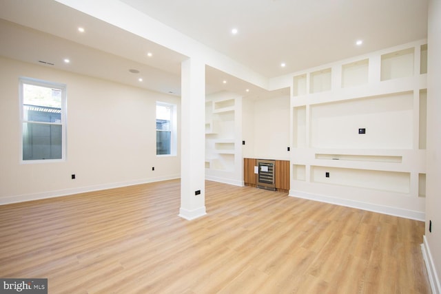 unfurnished living room featuring light wood-type flooring, beverage cooler, and built in features